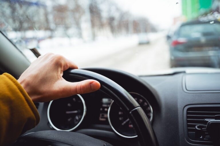 A man's hand is on the wheel of the car. Driving around the city. Transmission panel, black interior of the car,Speed control system.