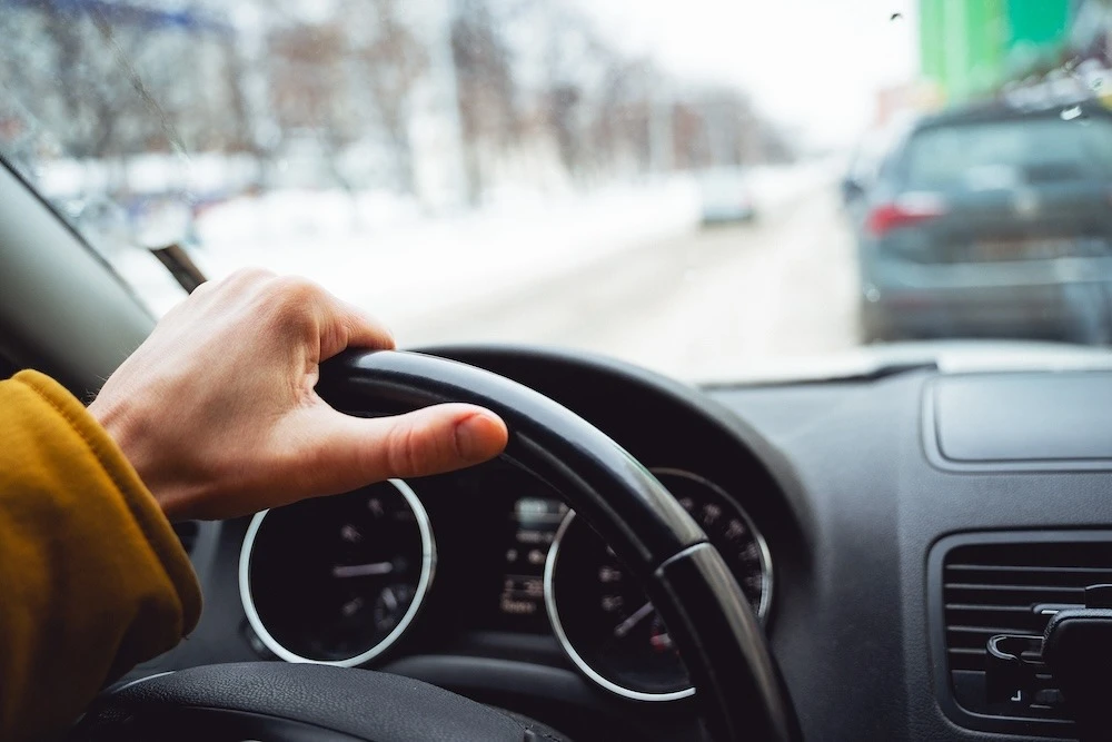 A man's hand is on the wheel of the car. Driving around the city. Transmission panel, black interior of the car,Speed control system.